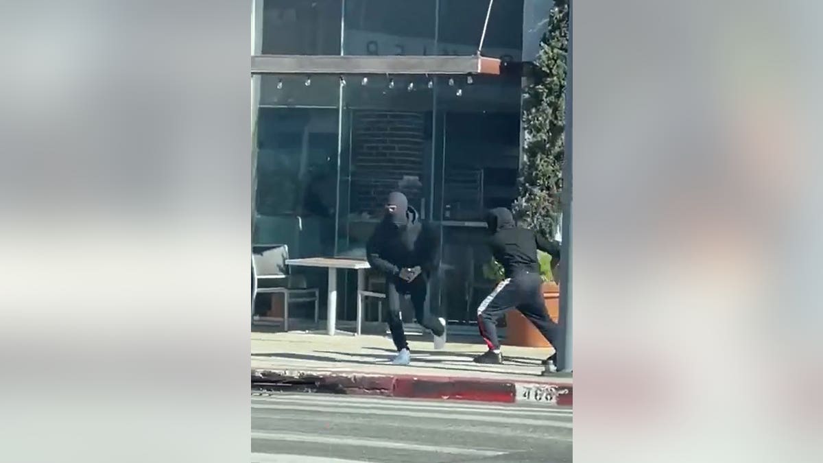 Two robbers dressed in all black, wearing ski masks, running after committing robbery
