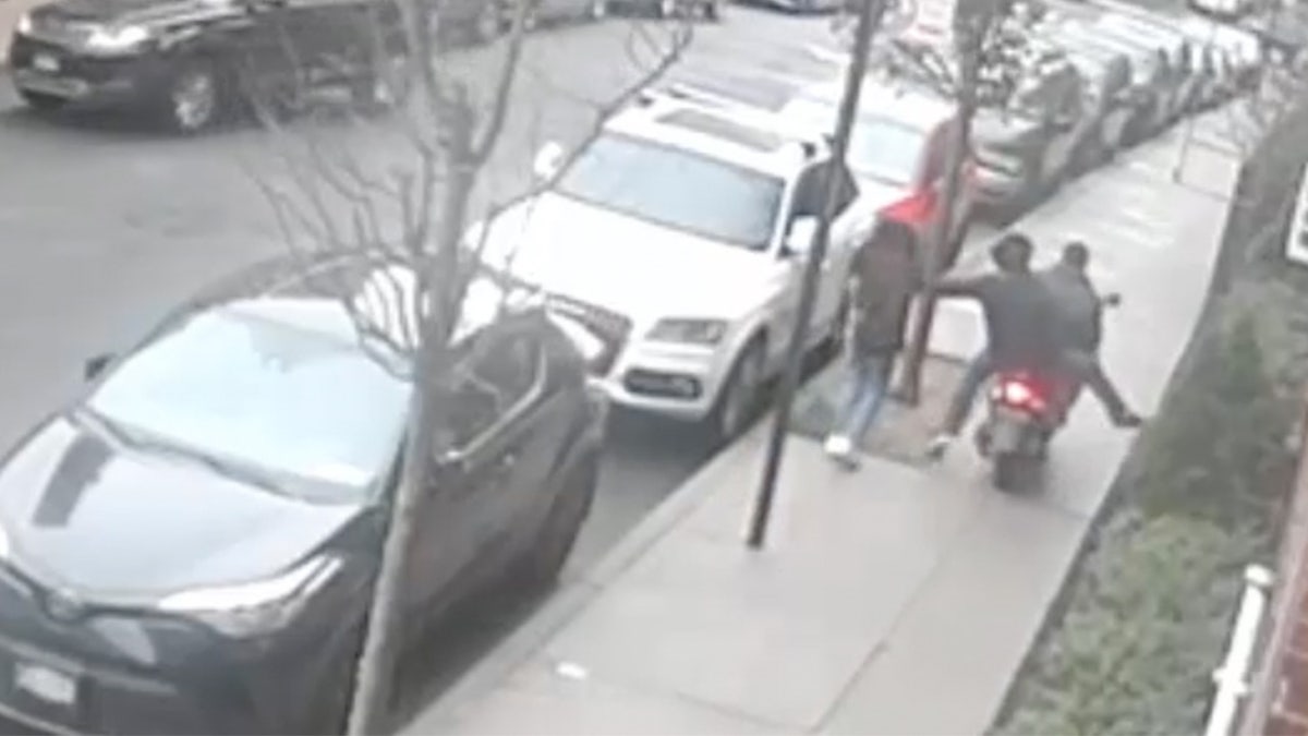 A surveillance footage still showing men on a scooter rip a necklace from girl.