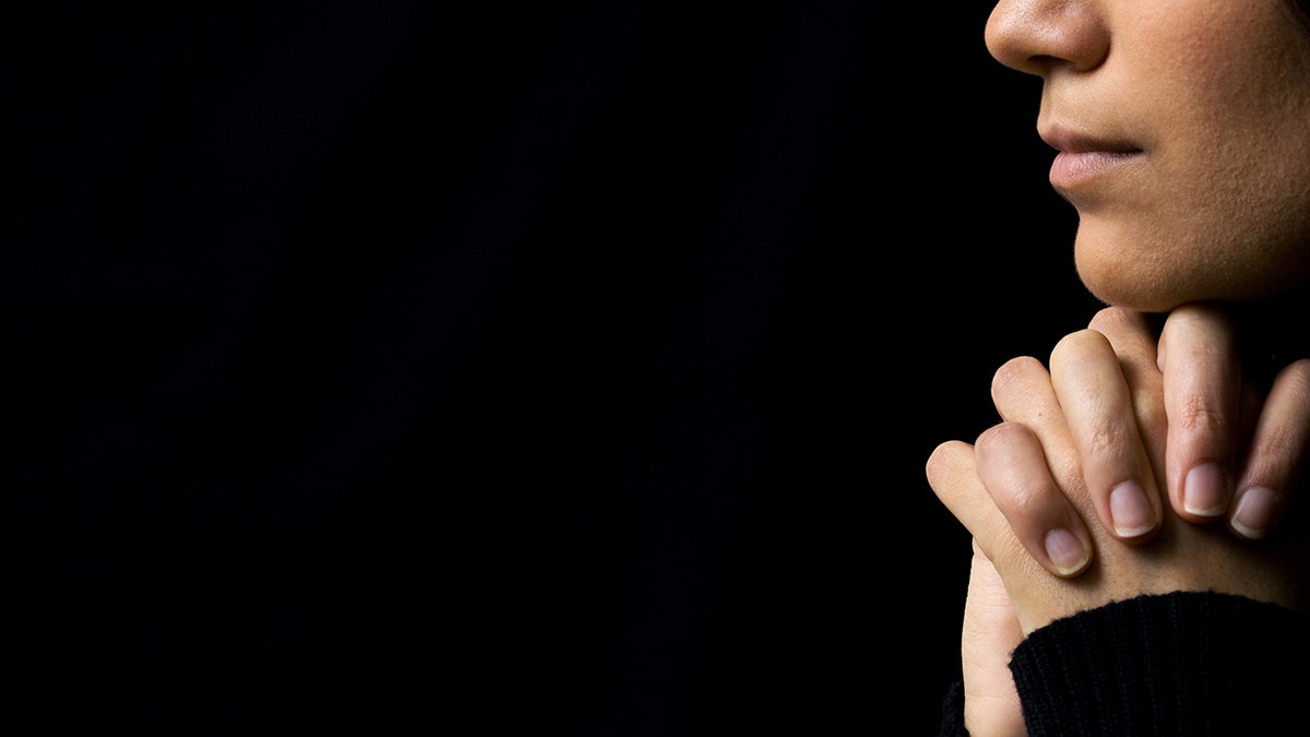 woman praying with hands folded under chin