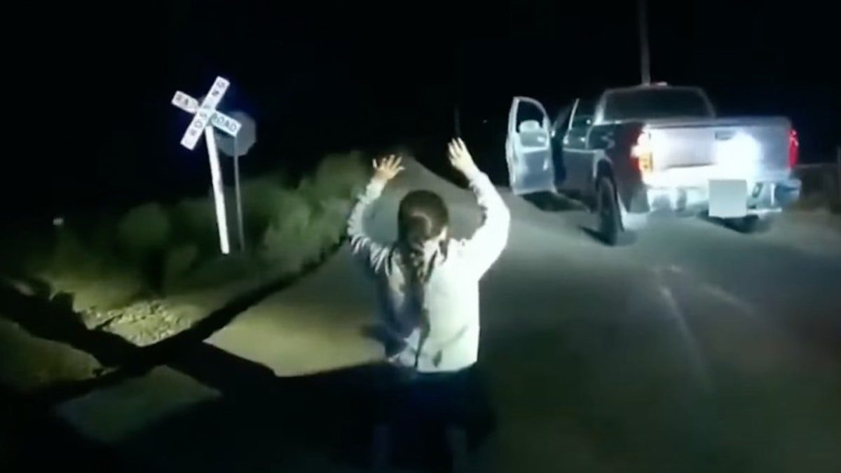 Yareni Rios-Gonzalez shown with her hands up at a railroad crossing.