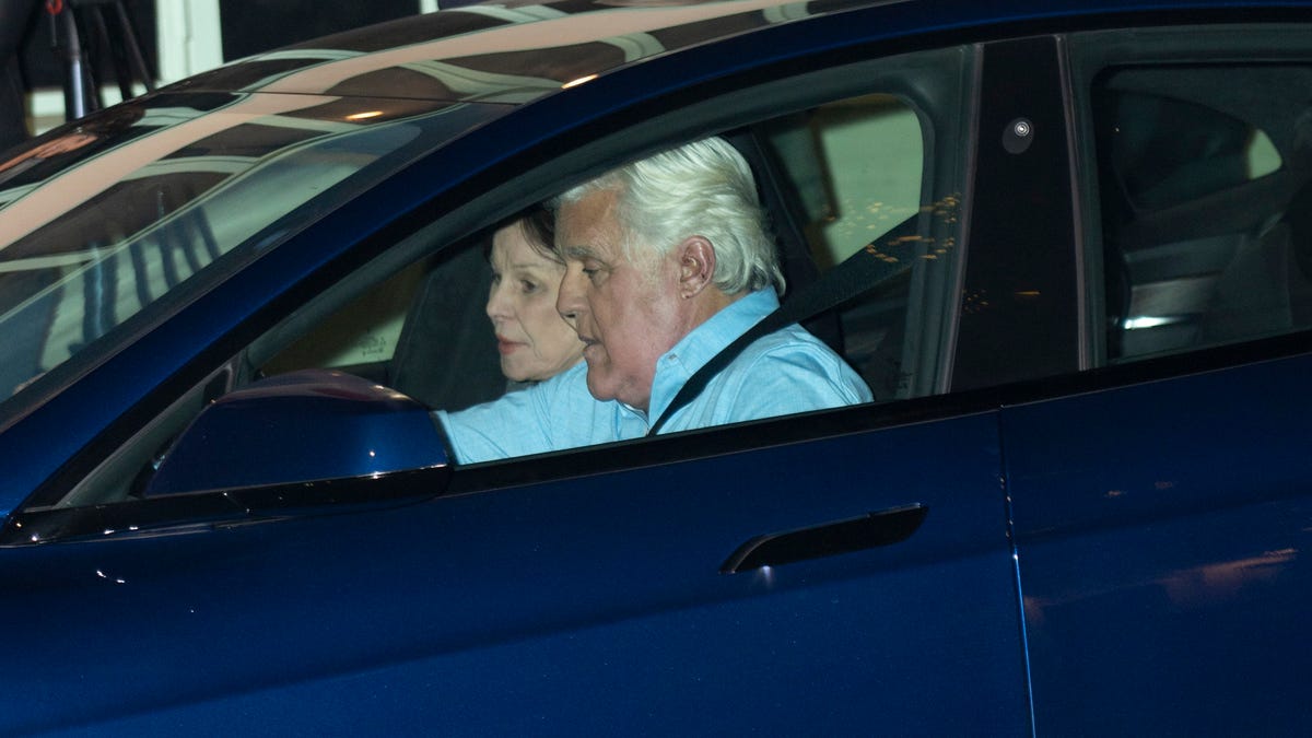 Jay leno in a blue shirt arrives at The Comedy & Magic Club with his wife Mavis in a blue Tesla