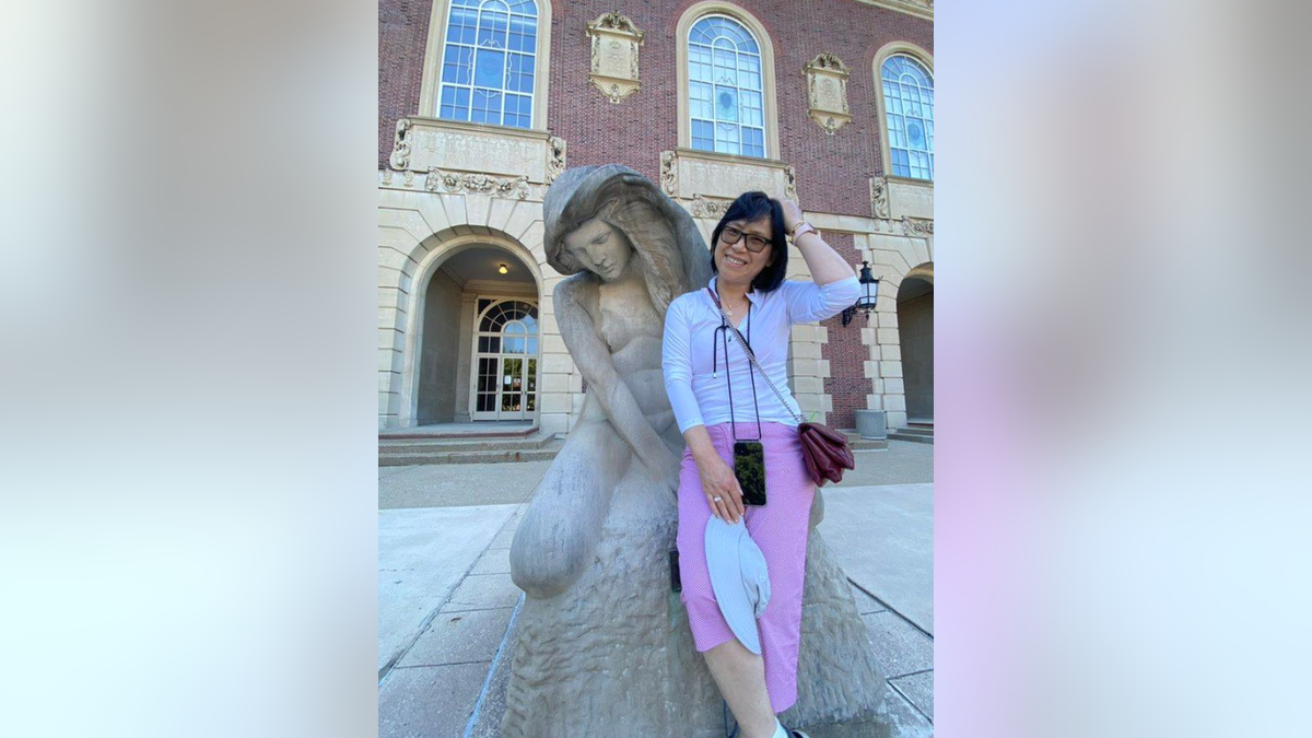 Lili Xu sitting next to a statue on a trip.