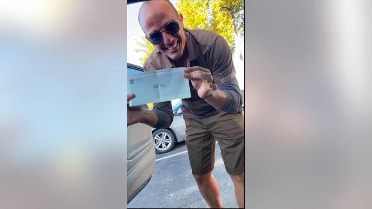 Yoel shows off his UPS paycheck, the first check he earned while working in America