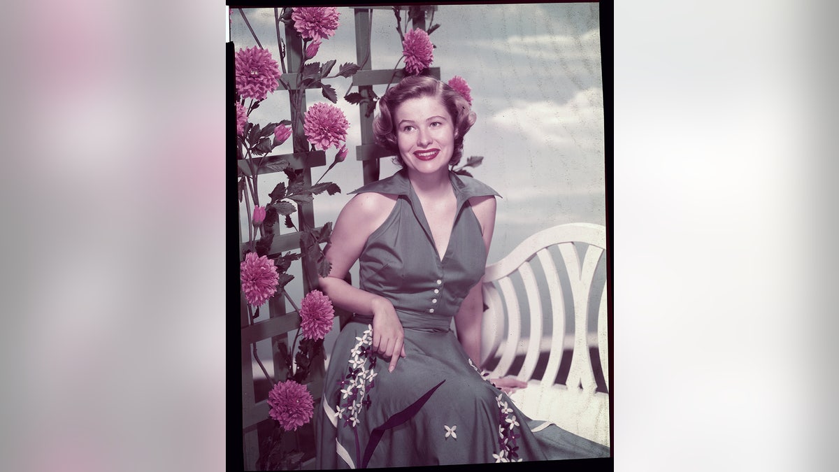 Nancy Olson Livingston surrounded by flowers.