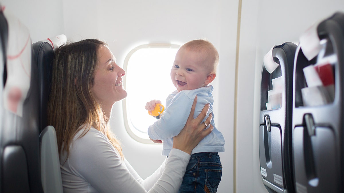 baby smiling on airplane with mother