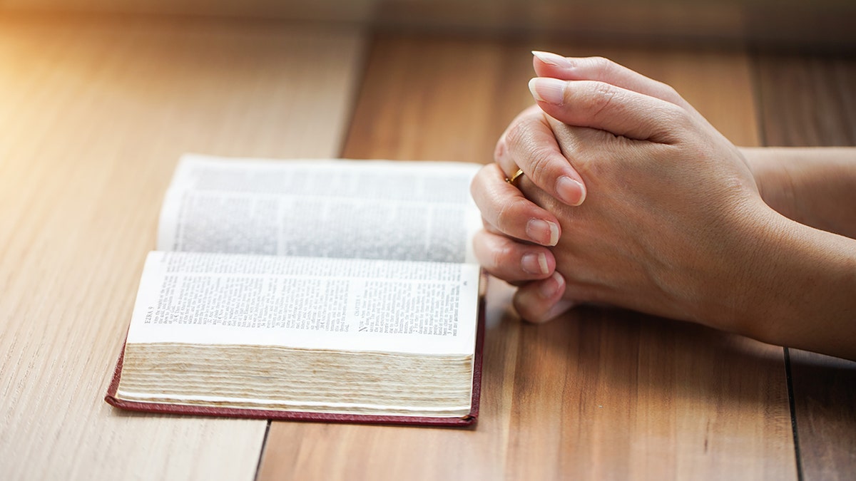 woman praying at desk with bible