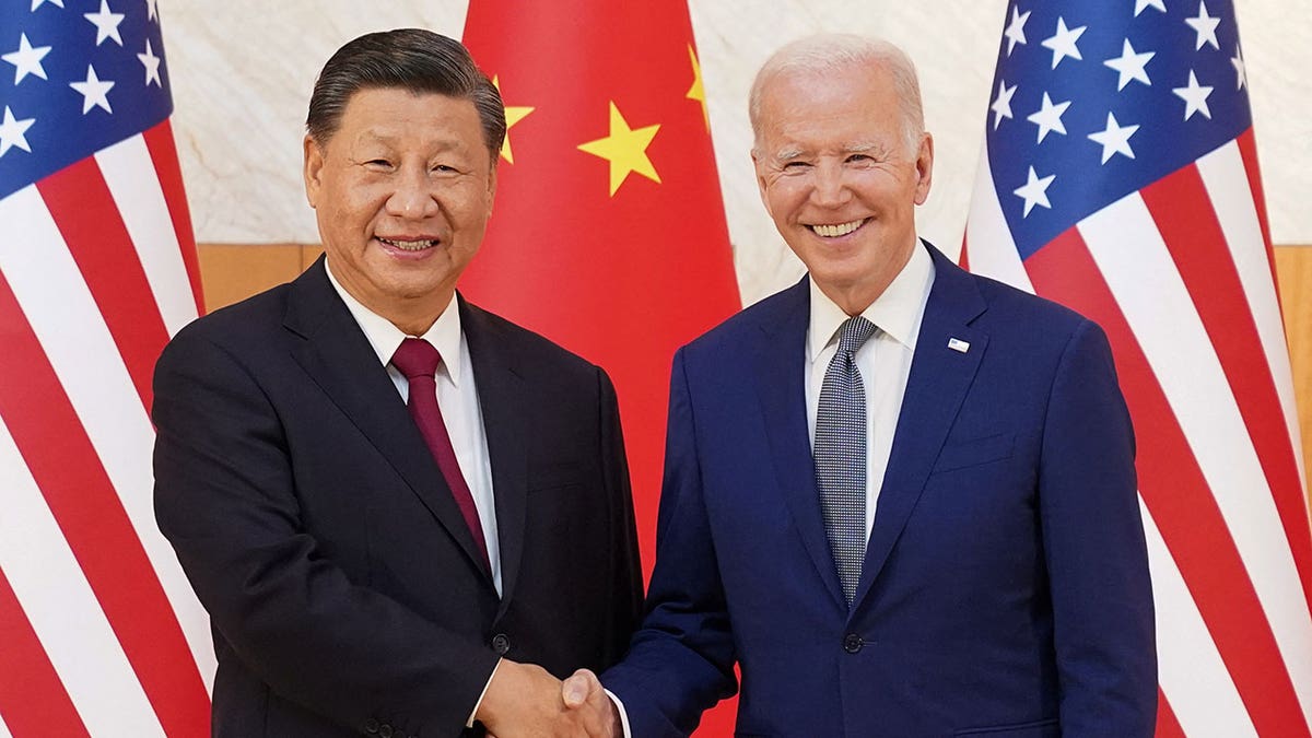 Xi Jinping, left, shakes hands with President Biden; US, China flags in background