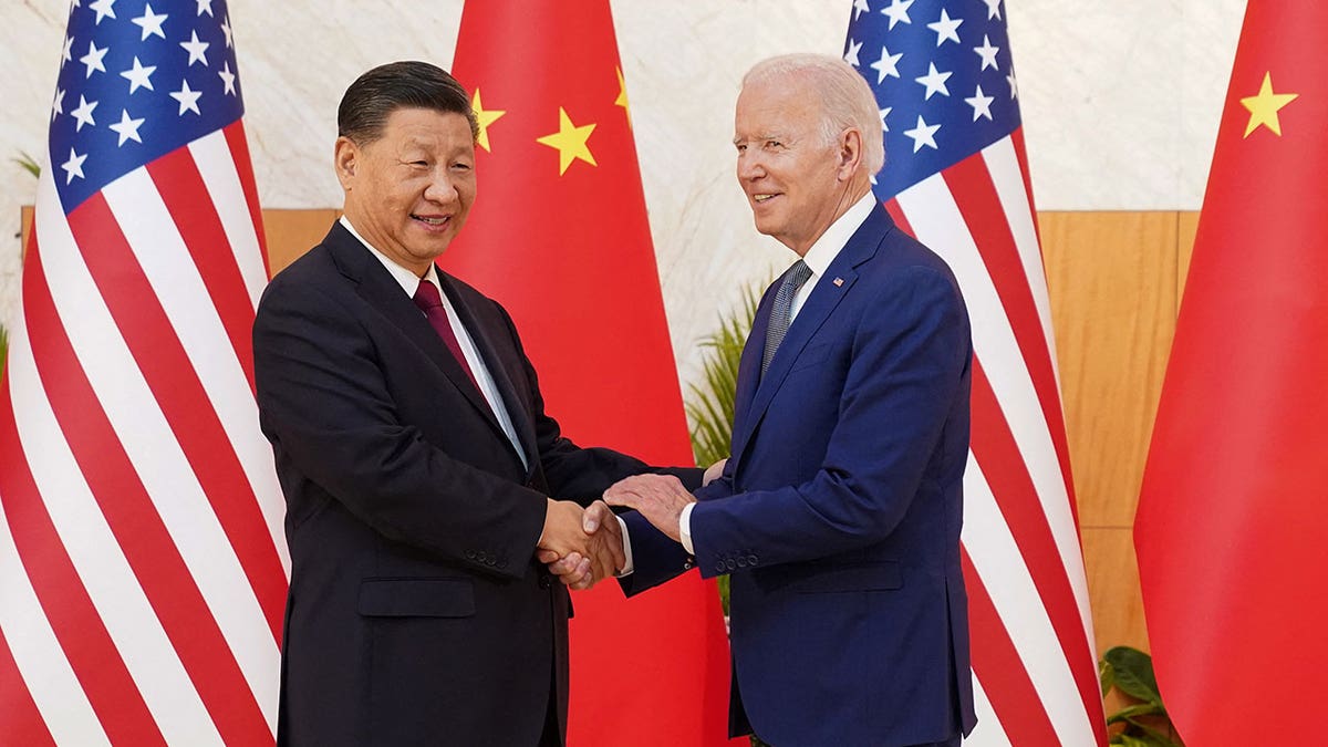 Biden and Xi shake hands in front of the Chinese and US flags