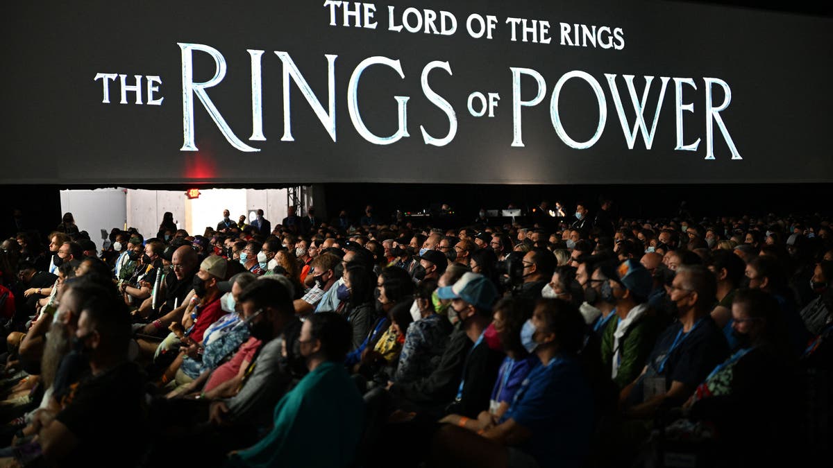 A black screen with "The Lord of the Rings: RIngs of Power" logo, crowd of fans below