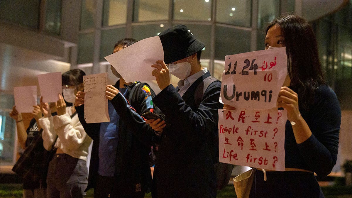 Chinese university students hold up signs during protest over covid restrictions