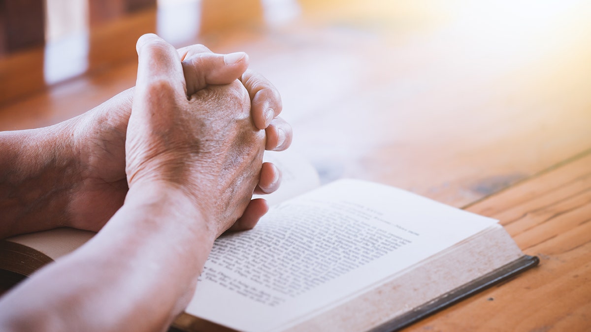 elderly woman praying over bible