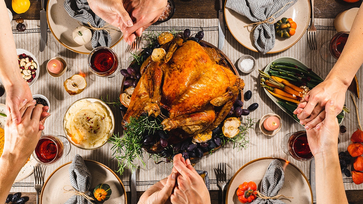 Family praying around holiday feast