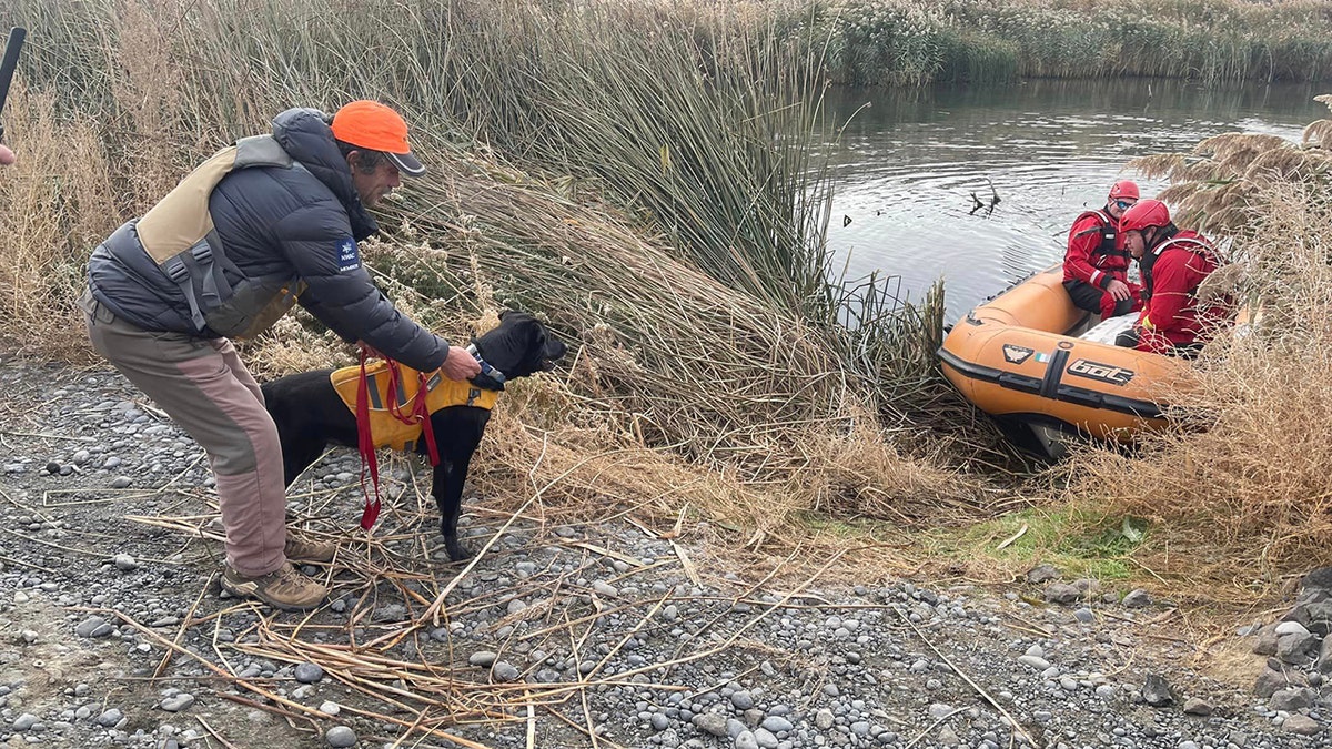 rescue team on small vessel and dog on shore