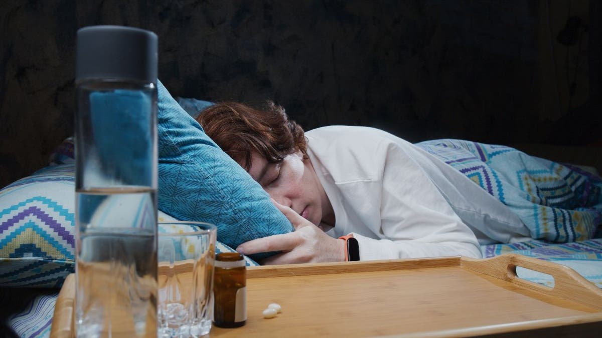 Person sleeping with water bottle near bed