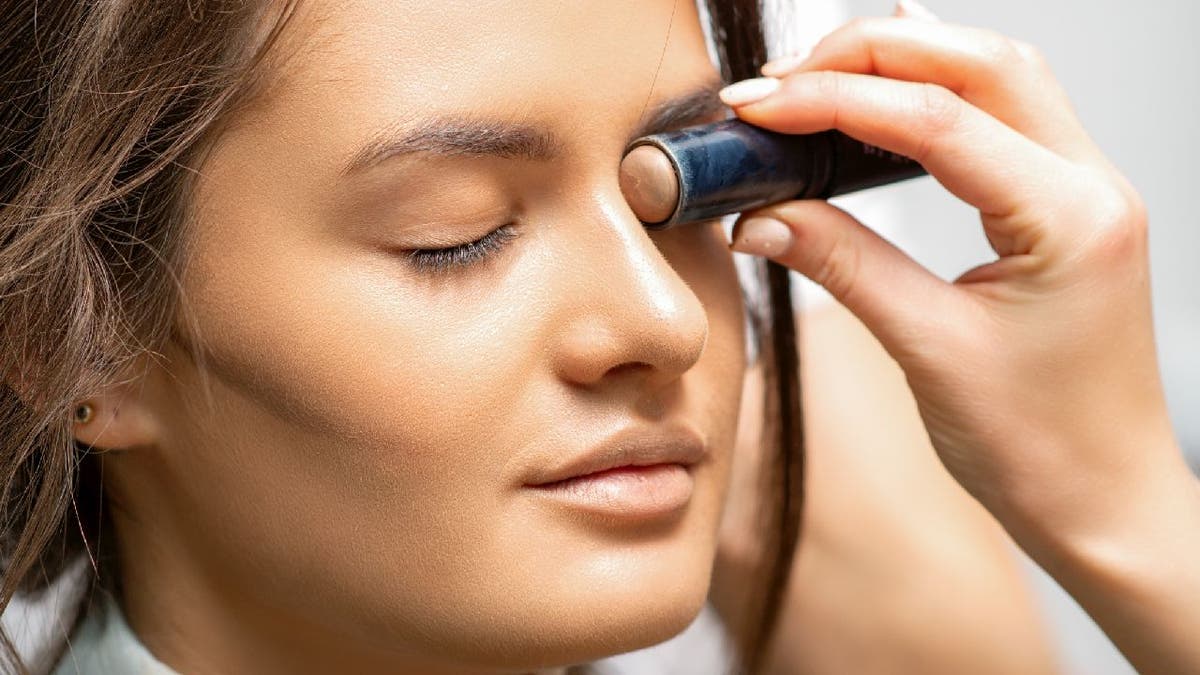 Woman getting makeup done with contour stick