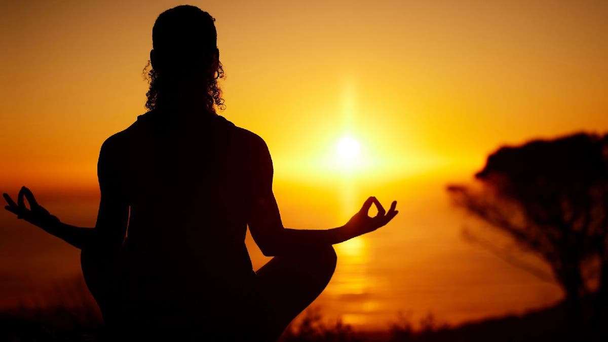 Woman meditates at sunset