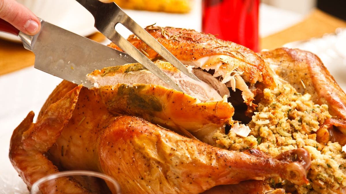 Close-up view of someone carving a turkey on a table