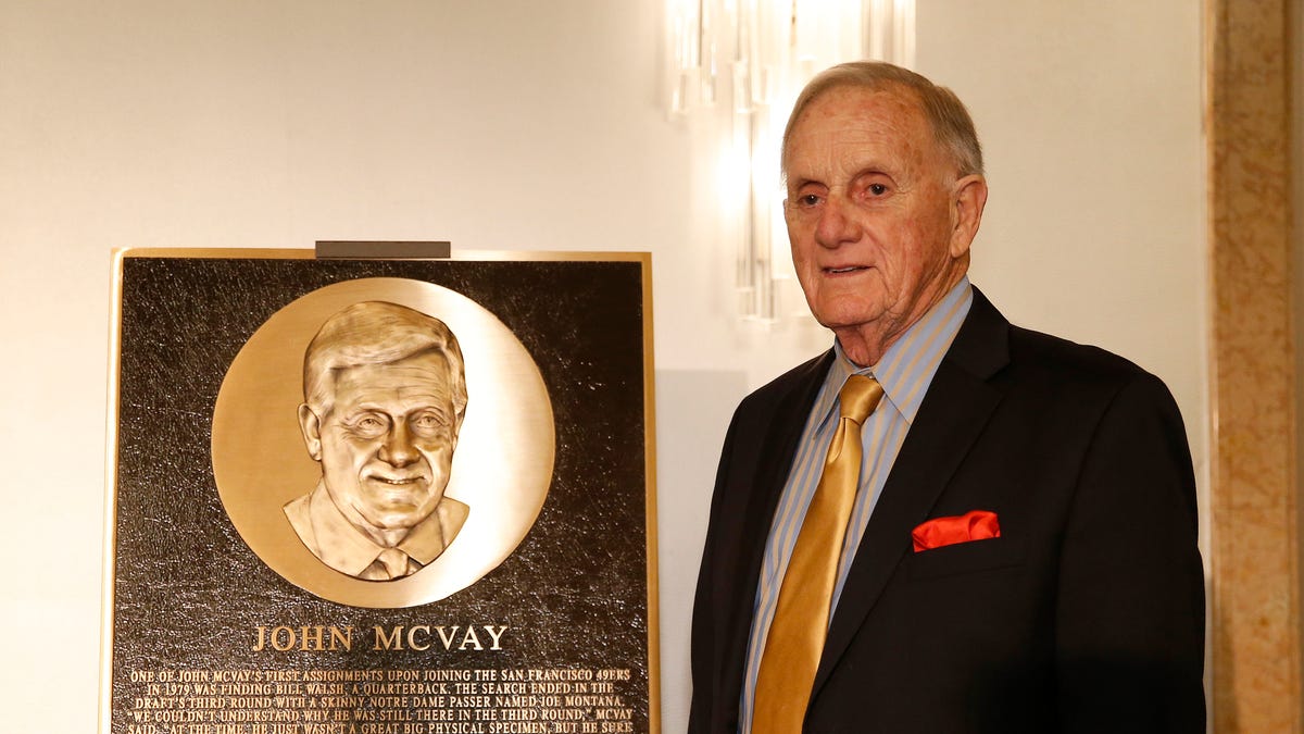 John McVay poses in front of plaque