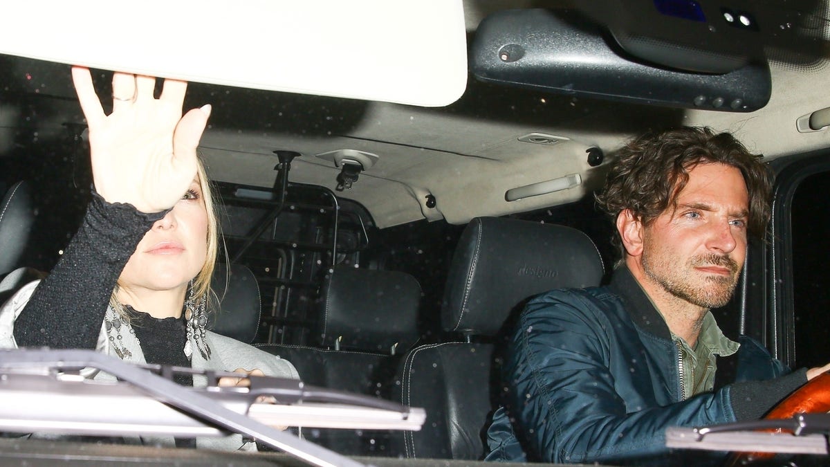 Bradley Cooper drives passenger Kate Hudson who is looking in the mirror to Leo DiCaprio's birthday