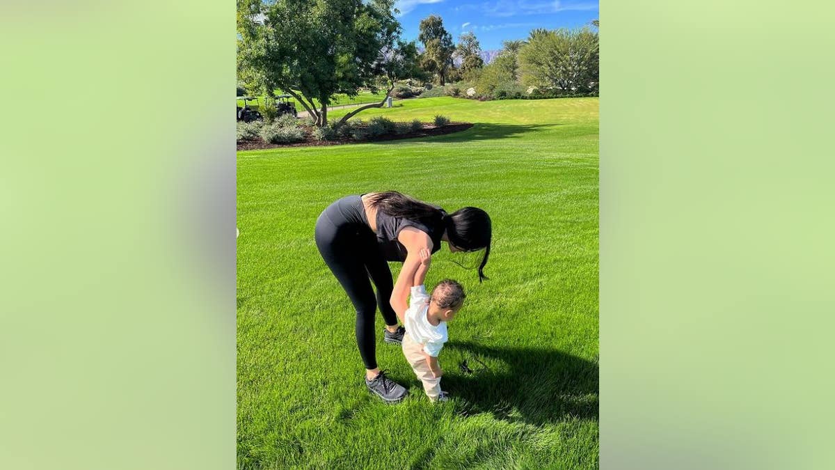 Kylie Jenner walks with her son on the grass outside