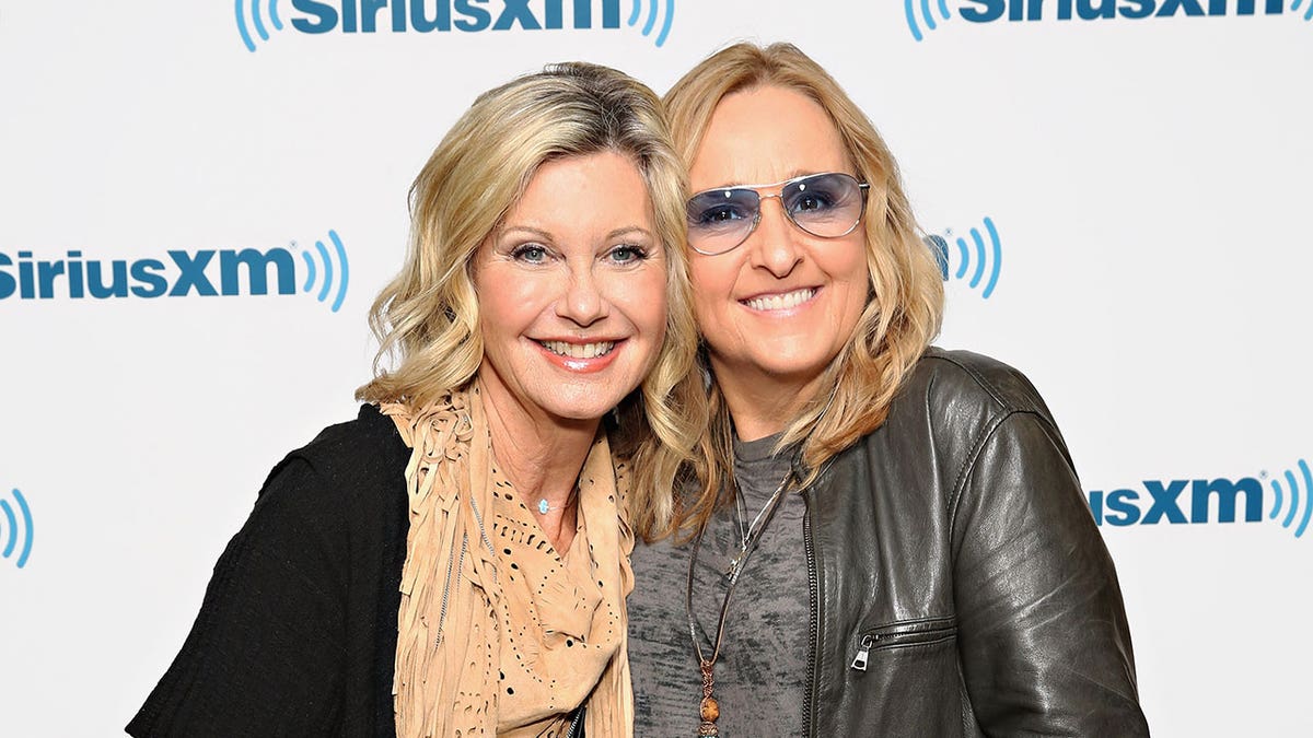 Olivia Newton-John and Melissa Ethridge smile side by side during a Sirius XM event 