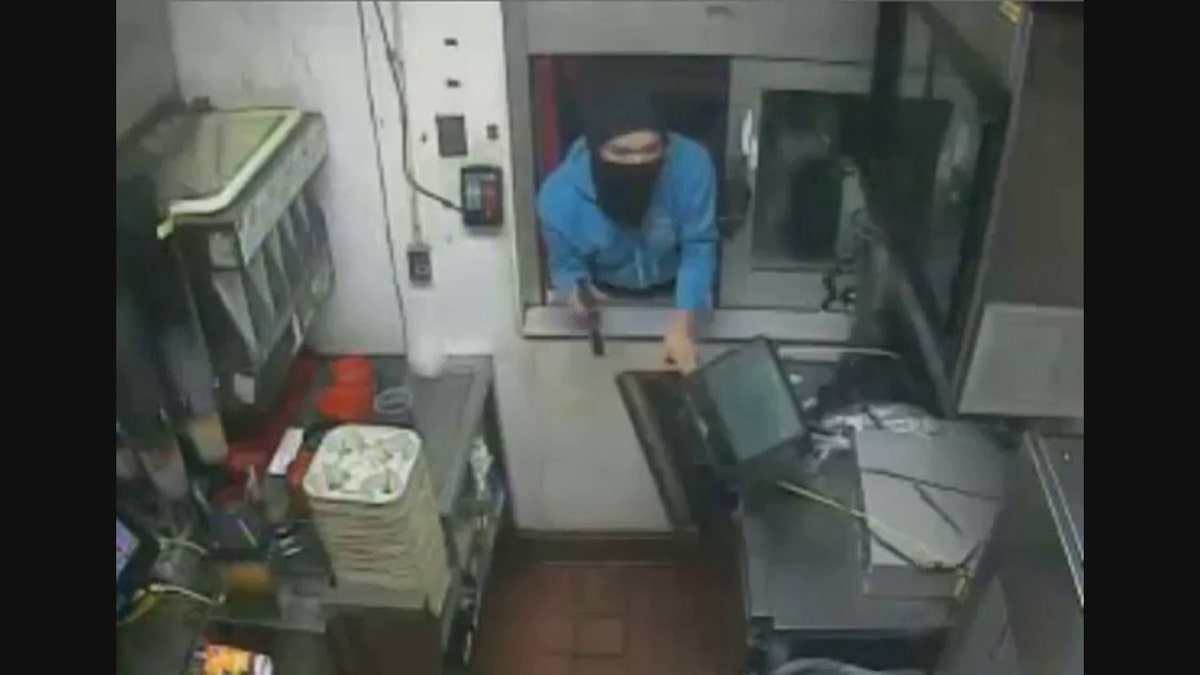 robber pointing gun at worker