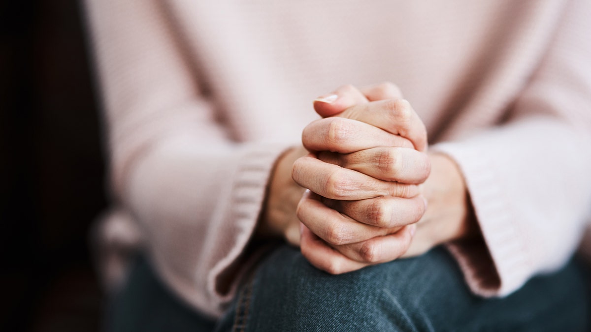 Woman praying with hands folded on knees