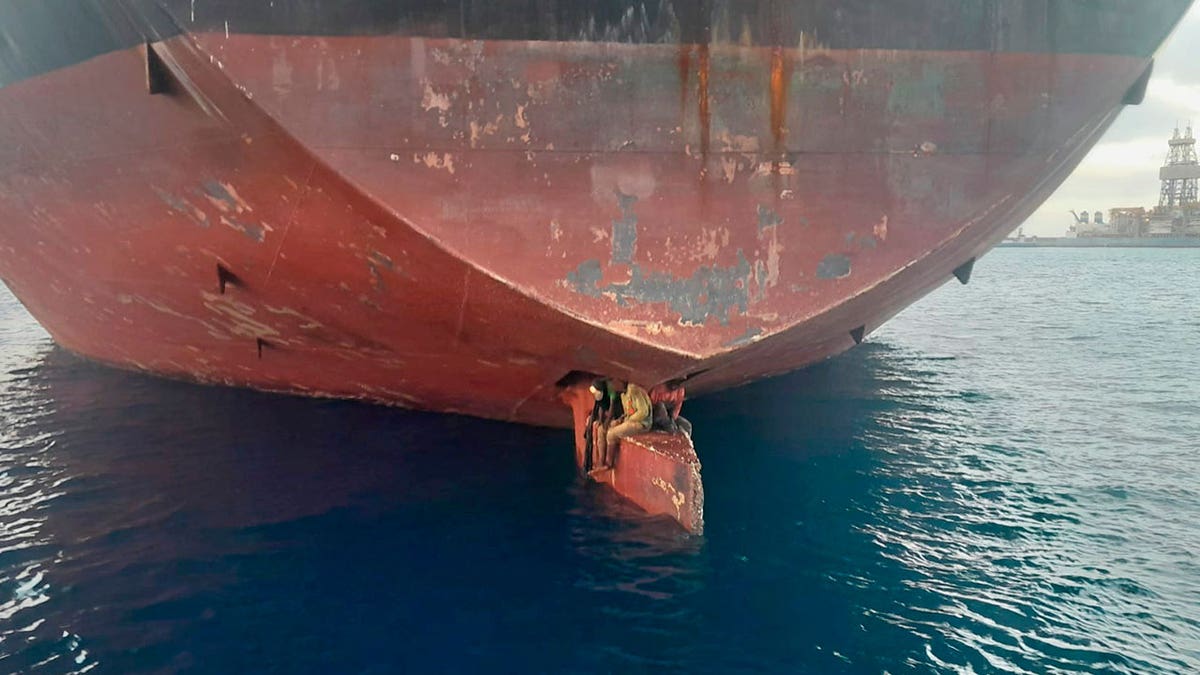 Three men sit on hull of oil tanker ship in Canary Islands