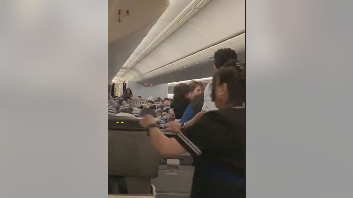 A flight attendant runs down the aisle during confrontation with passenger