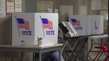 Man sitting in voting booth casting his vote. Sitting behind voting privacy booth