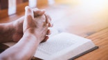 elderly woman praying over bible