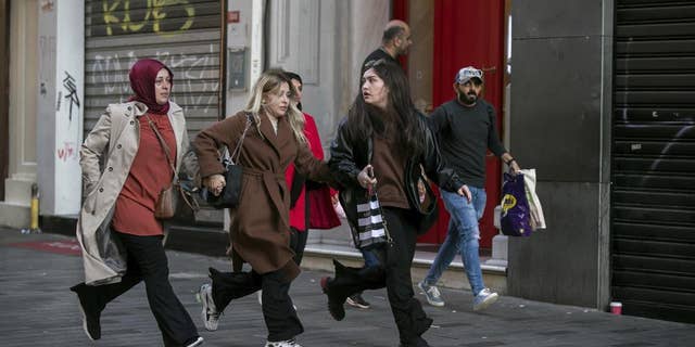 People leave the area after an explosion on Istanbul's popular pedestrian Istiklal Avenue Sunday, Istanbul, Sunday, Nov. 13, 2022. A bomb exploded on a major pedestrian avenue in the heart of Istanbul on Sunday, killing a handful of people, wounding dozens and sending people fleeing as flames rose.