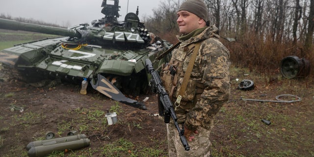 A Ukrainian service member stands next to a damaged Russian T-72 BV tank as the Russian attack on Ukraine continues.