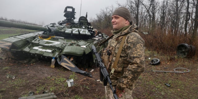 A Ukrainian service member stands next to a damaged Russian T-72 BV tank as the Russian attack on Ukraine continues.