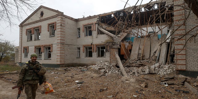 A Ukrainian serviceman walks past a building of a kindergarten damaged during a Russian missile attack in the village of Novooleksandrivka, in Kherson region, Ukraine Nov. 9, 2022.