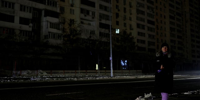 A woman with a dog waits for a bus on a street without power after a critical civilian infrastructure was hit by Russian missiles, in Kyiv, Ukraine, on November 23, 2022.