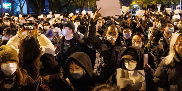 Des gens tiennent des feuilles de papier blanches pour protester contre les restrictions du COVID-19, après une veillée pour les victimes d'un incendie à Urumqi, alors que les épidémies de coronavirus se poursuivent à Pékin, le 27 novembre 2022.