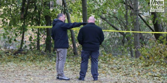 Investigators stand in the parking lot behind the home where four University of Idaho students were brutally murdered and point toward the third-floor window.