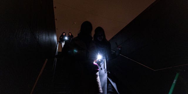Pedestrians use flashlights as they walk during a power cut in downtown Kyiv, Ukraine, on Nov. 10, 2022.