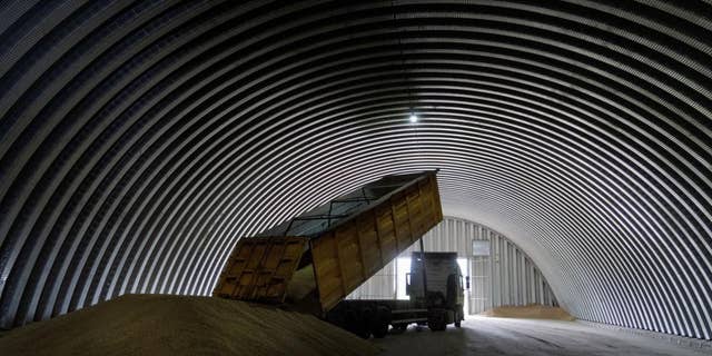 A dump truck unloads grain into a barn in the village of Zghurivka, Ukraine, on August 9, 2022.