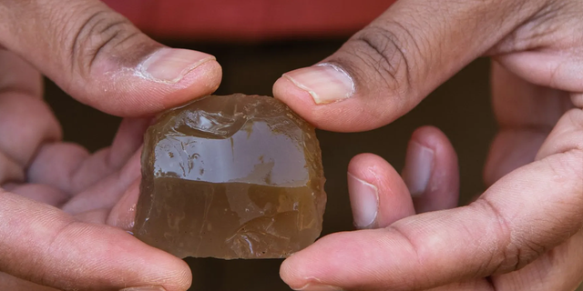 An archeologist holds a French musket flint found from one of the Continental burials.