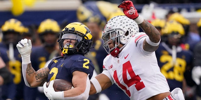 Michigan running back Blake Corum is chased by Ohio State safety Ronnie Hickman on November 27, 2021 in Ann Arbor.