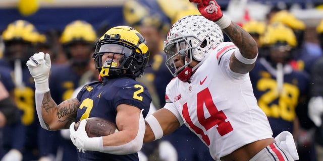 Michigan running back Blake Corum is chased by Ohio State safety Ronnie Hickman on November 27, 2021 in Ann Arbor.