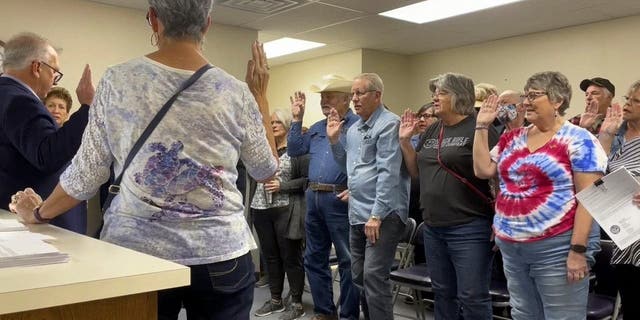 In this image from video, Nye County Clerk Mark Kampf, far left, in suit, swears in a group of residents who will hand-count early ballots cast in the rural county about halfway between Las Vegas and Reno, Oct. 26, 2022, in Pahrump, Nev. 