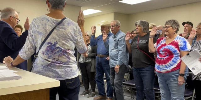 In this image from video, Nye County Clerk Mark Kampf, far left, in suit, swears in a group of residents who will hand-count early ballots cast in the rural county about halfway between Las Vegas and Reno, Oct. 26, 2022, in Pahrump, Nev. 