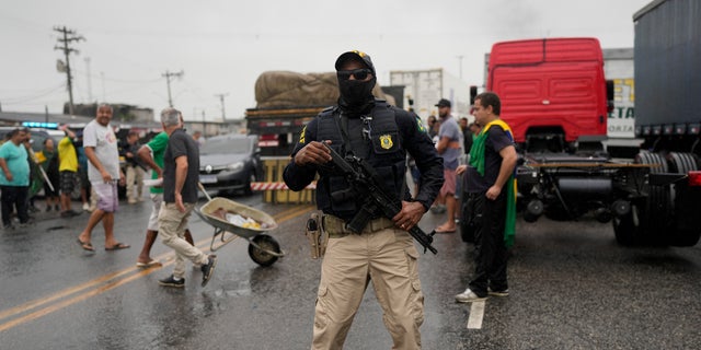 Highway Federal Police, keep watch as truckers supportive of President Jair Bolsonaro block a highway to protest his run-off election loss to former President Luiz Inacio Lula da Silva in Itaborai, Rio de Janerio state, Brazil, Tuesday, Nov. 1, 2022.