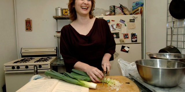 Julie Powell chops leeks to make potato leek soup, one of the first recipes in Julia Child's "Mastering the Art of French Cooking," shown at left, in her apartment in New York on Sept. 30, 2005.