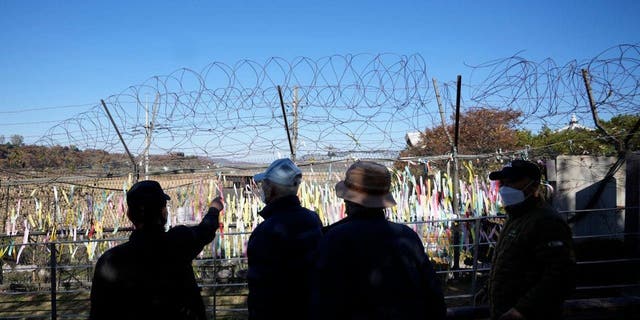Visitors walk near the wire fences decorated with ribbons with messages wishing for the peace of the two Koreas at the Imjingak Pavilion in Paju, South Korea, Friday, Nov. 4, 2022. 