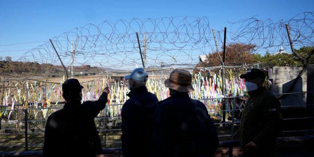 Visitors walk near the wire fences decorated with ribbons with messages wishing for the peace of the two Koreas at the Imjingak Pavilion in Paju, South Korea, Friday, Nov. 4, 2022. 