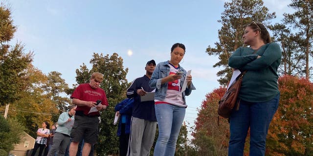Voters fill out forms as they wait in line to cast ballots in the last hour of early voting in the Atlanta suburb of Tucker, Ga., on Friday, Nov. 4, 2022.